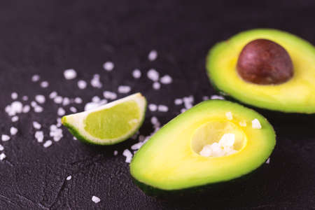 Avocado, sea salt and lime slices on stone background. Healthy food concept