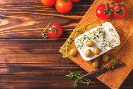 Greek cheese feta with thyme and green olives on rustic wooden table. Selective focusの写真素材