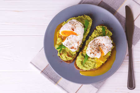 Rye bread toast with poached egg, puree avocado, spices and arugula. Continental breakfast. Healthy food concept. Selective focusの写真素材
