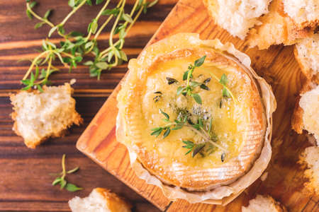 Traditional French homemade baked Camembert cheese with thyme and baguette bread. European cuisine. Selective focus.の写真素材