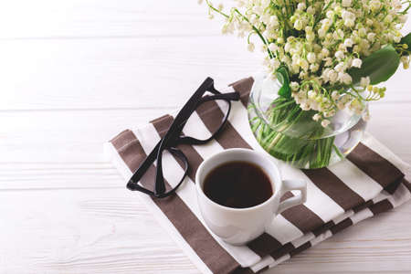 Cup of coffee, glasses and snowdrops flowers on white wooden table. Lifestyle concept. Selective focusの写真素材