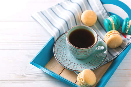 Cup of coffee and macaron cakes on tray on white wooden table. Lifestyle concept. Selective focusの写真素材