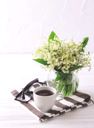 Cup of coffee, glasses and snowdrops flowers on white wooden table. Lifestyle concept. Selective focusの写真素材