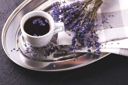 Cup of coffee with lavender flowers on dark stone table. Lifestyle concept. Selective focusの写真素材