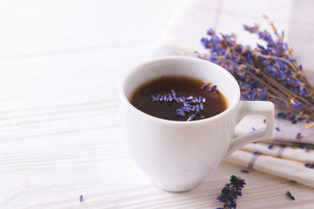 Cup of coffee with lavender flowers on white wooden table. Lifestyle concept. Selective focusの写真素材