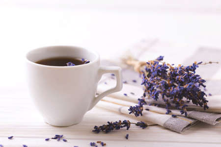 Cup of coffee with lavender flowers on white wooden table. Lifestyle concept. Selective focusの写真素材