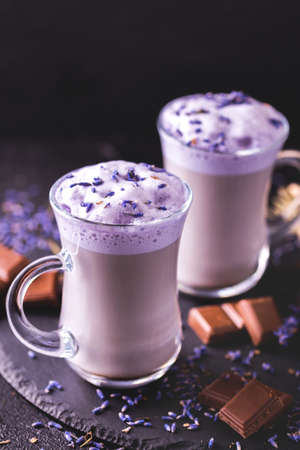 Coffee cup of cappuccino with homemade lavender and chocolate syrup and flowers on tray. Cozy breakfast.の写真素材