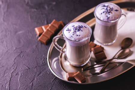 Coffee cup of cappuccino with homemade lavender and chocolate syrup and flowers on tray. Cozy breakfast.の写真素材