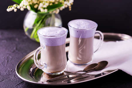 Coffee cup of cappuccino with homemade lavender and chocolate syrup and flowers on tray. Cozy breakfast.の写真素材