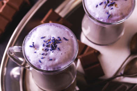 Coffee cup of cappuccino with homemade lavender and chocolate syrup and flowers on tray. Cozy breakfast.の写真素材