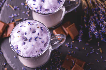 Coffee cup of cappuccino with homemade lavender and chocolate syrup and flowers on tray. Cozy breakfast.の写真素材