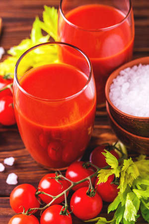 Glasses of tomato juice with sea salt and celery on wooden background. Healthy food concept.の写真素材