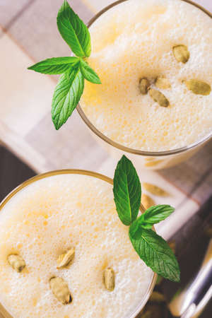 Traditional Indian mango lassi curd with cardamon, mint, vanilla and saffron served in terracotta glasses. Kesariya. Keshariya. Kesar. Yogurt smoothieの写真素材