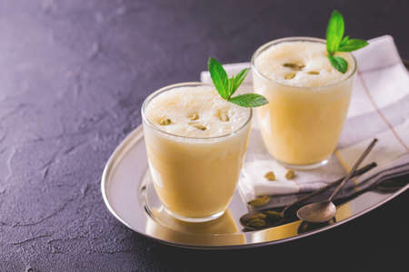 Traditional Indian mango lassi curd with cardamon, mint, vanilla and saffron served in terracotta glasses. Kesariya. Keshariya. Kesar. Yogurt smoothieの写真素材