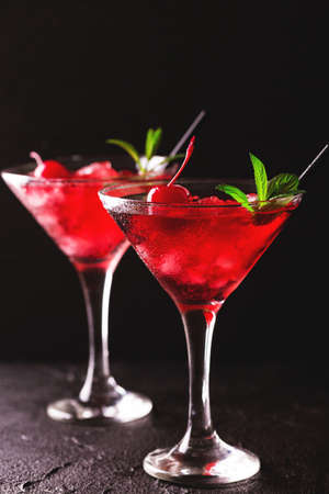 Strawberry daiquiri cocktail with lime, strawberry syrop, cherry and mint on black background. Summer drink, refreshment, Aperitif. Selective focusの写真素材