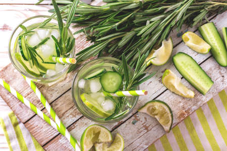 Cold rosemary, lime and cucumber lemonade on the rustic wooden cutting board. Healthy drink and summer refreshment concept. Copyspace, top viewの写真素材