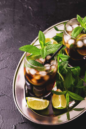 Cuba Libre cocktail with cola, lime, dark or light rum and peppermint on black background. Summer refreshment. Selective focus. Copyspace, Top viewの写真素材