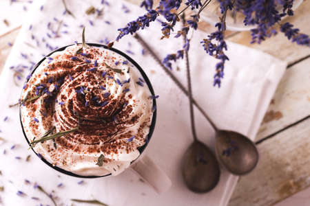 Two cups of hot chocolate or cacao with whipped cream, lavender and chocolate on white wooden tableの写真素材