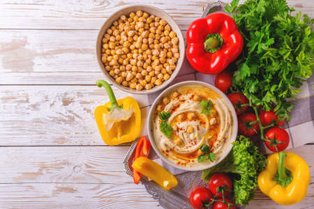 Traditional homemade hummus and chickpea served with vegetables and spices on wooden table. Jewish Cuisine. Top viewの写真素材