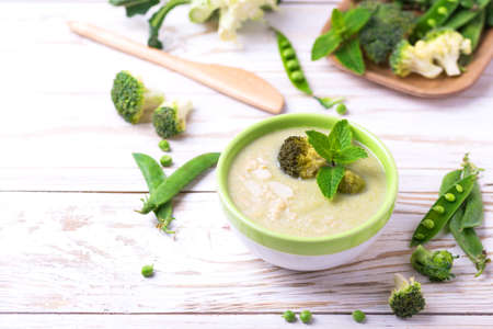 Broccoli and green peas puree soup decorated with mint leafes and almond flakes. Selective focus. Concept of healthy food. Vegetarian. Vegan. Horizontal view. Copyspaceの写真素材