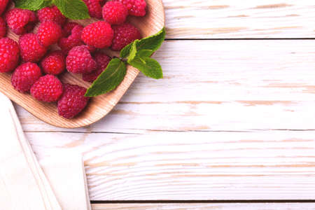 Fresh organic ripe raspberry with mint leaves in tray on wooden table background. Concept of healthy food. Top viewの写真素材