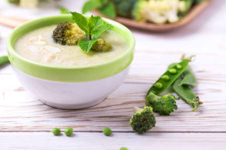 Broccoli and green peas puree soup decorated with mint leafes and almond flakes. Selective focus. Concept of healthy food. Vegetarian. Vegan. Horizontal viewの写真素材