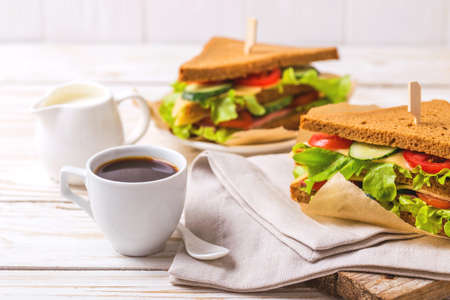 Rye bread sandwich with ham, cheese, cherry tomatoes, cucumber and lettuce and espresso coffee for breakfast. Selective focusの写真素材