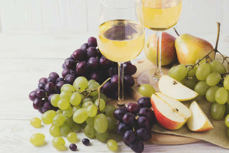 Cheese plate served with two glasses of white wine, fresh grapes and pears on white wooden background. Copyspace.  Horizontal Viewの写真素材