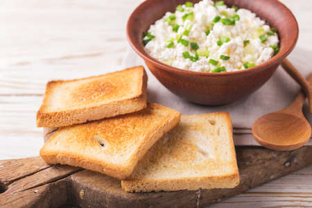 Clay bowl of goat cream cheese with green onions and olive oil, dip sauce on wooden table, top viewの写真素材