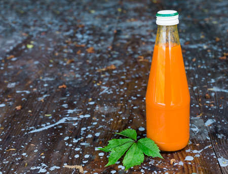 Bottled carrot juice on wooden backgroundの写真素材