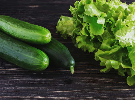 Green salad, cucumbers  on black rustic wooden backgroundの写真素材