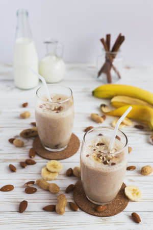 Peanut and almond butter banana oat smoothie with paper straws on a wooden rustic tableの写真素材