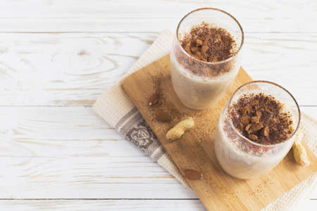 Peanut and almond butter banana oat smoothie with paper straws on a wooden rustic tableの写真素材