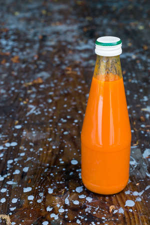 Bottled carrot juice on wooden backgroundの写真素材