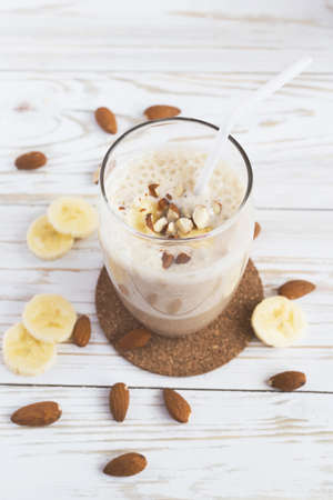 Peanut and almond butter banana oat smoothie with paper straws on a wooden rustic tableの写真素材