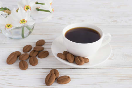 cookies and narcissus and cup of coffee on white wooden backgroundの写真素材