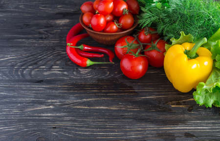Concept of vegetarian food with tomatoes on vine, paprika, red chilli, basil,  parsley, dill and...