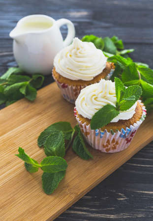 Homemade tiramisu cupcakes with leafs of mint and whipped cream on dark rustic wooden background.の写真素材