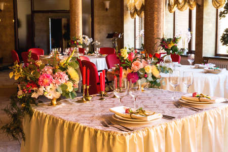 Elegant beautiful decorated table with utensils, vases of flowers and tableware.