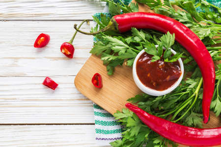 Tomato sauce salsa, hot chili and basil, ketchup on wooden background.