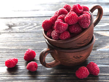 Fresh sweet raspberry in clay bowl on the wooden table