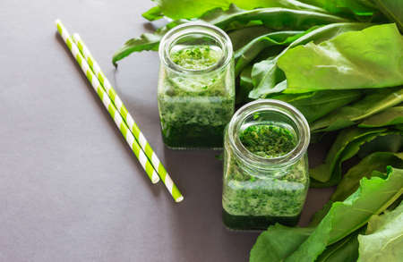 Healthy green sorrel and spinach smoothie in glass jar with dark background.