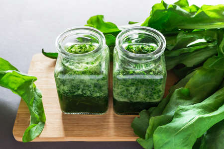 Healthy green sorrel and spinach smoothie in glass jar with dark background.