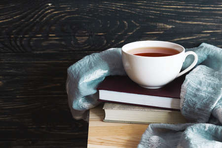 Warm knitted plaid, cup of hot tea and books on wooden table. Background with copy Space.の写真素材