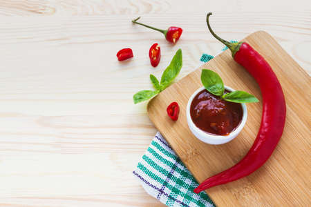Tomato sauce salsa, hot chili and basil, ketchup  on wooden background.