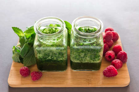 Healthy green smoothie with  raspberries and mint, milk shake in glass jar with dark background.の写真素材