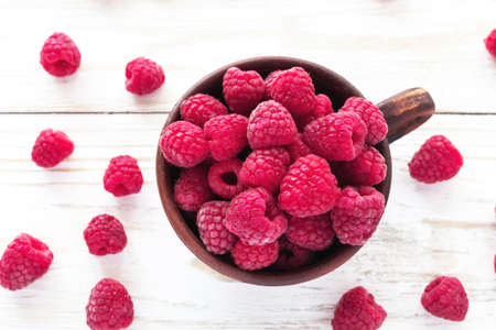 Fresh sweet raspberry in clay bowl on the wooden tableの写真素材