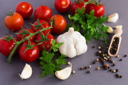 Parsley, garlic, fresh tomatoes on vine and spices, allspice, on dark background.の写真素材