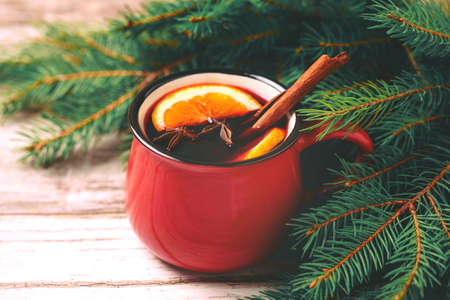 Hot mulled wine with orange, anise, cardamon and cinnamon on slate marble background. Christmas tree branches and cones. Flat lay, copy space, horizontal view. Holidays.の写真素材
