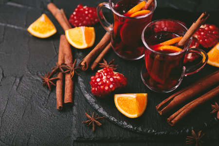 Hot mulled wine with apples, pomegranate, orange, anise and cinnamon with fresh fruits on slate marble background. Flat lay, copy space, top view. Christmas and holidays foodの写真素材
